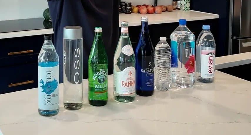 The eight bottled waters tested, lined up on a kitchen counter: Icelandic Glacial, Voss, Mountain Valley, Acqua Panna, Saratoga, Deer Park, Fiji and Evian.